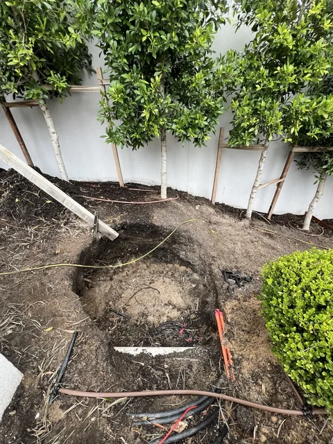 Garden bed with exposed irrigation lines, soil and trees at the Melbourne project site