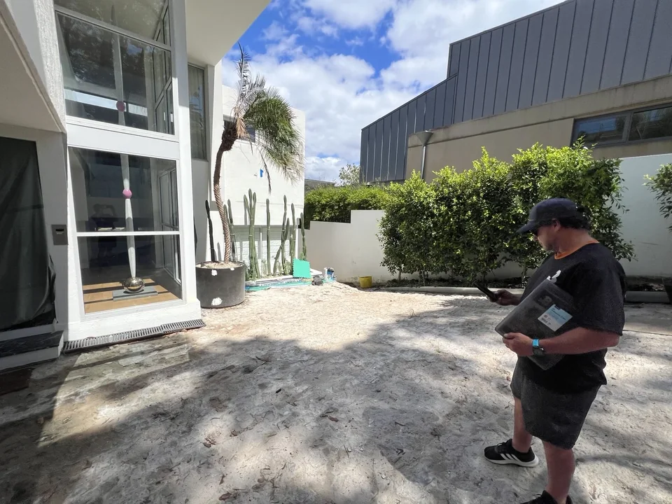 JB crew member assessing a Melbourne courtyard with a large potted palm and surrounding trees