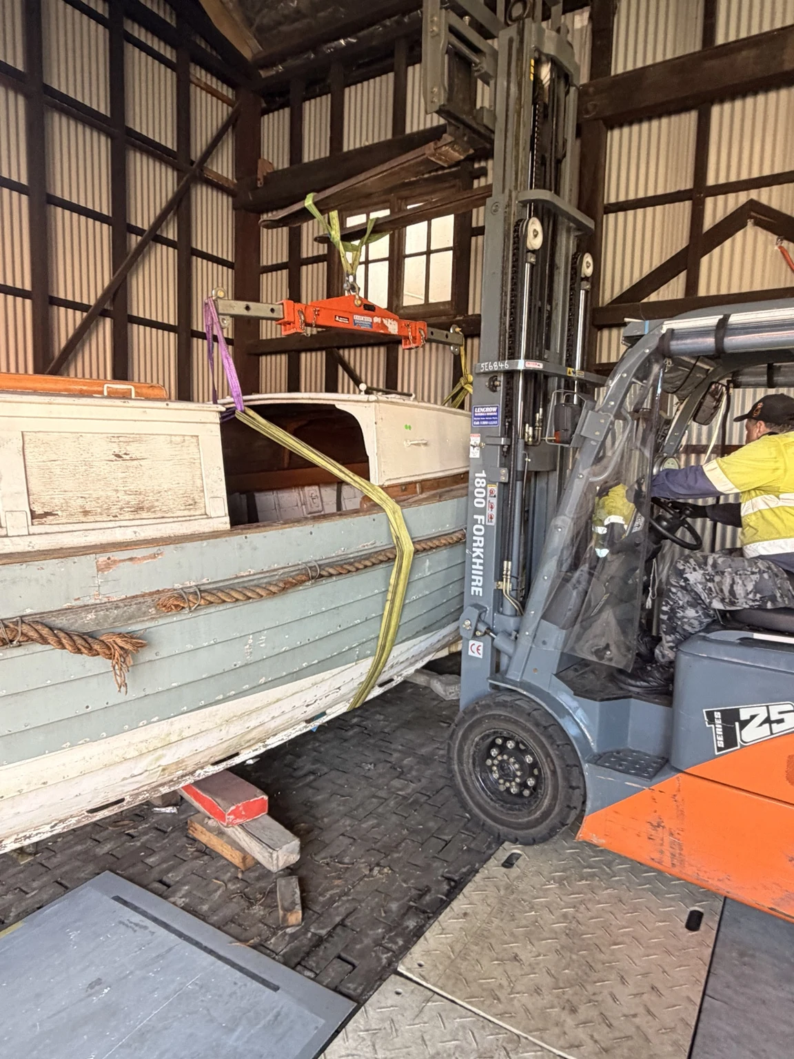 Side view of the boat and forklift inside the heritage building.