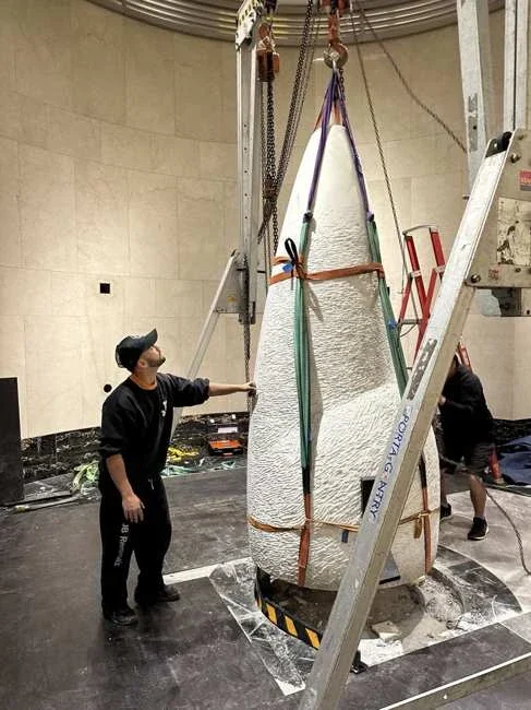 JB marble sculpture beneath a gantry with lifting slings